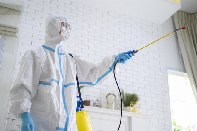 a-medical-staff-in-ppe-suit-is-using-disinfectant-spray-in-living-room-free-photo